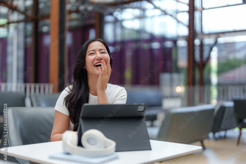 Woman laughing at her tablet, not looking at camera